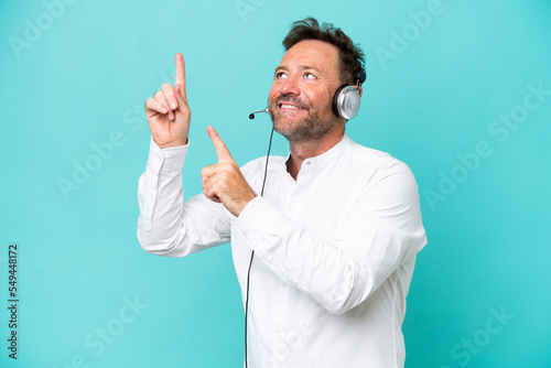 Telemarketer caucasian man working with a headset isolated on blue background pointing with the index finger a great idea