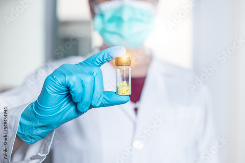 Scientist woman shows pale yellow solid in vial glass of flavonoids compound from extraction and isolation by chromatography in laboratory. Flavonoid substances are used for pharmaceuticals, medicine.