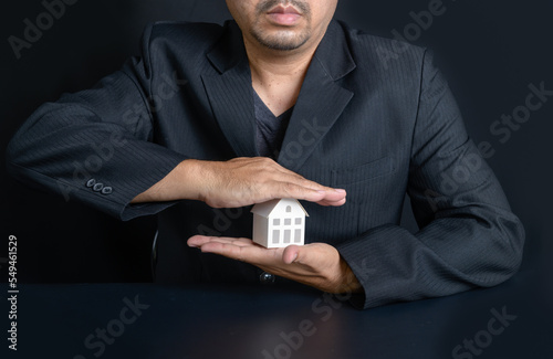 paper house that businessmen are using their hands to protec photo