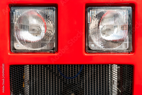 A big tractor on the road. Modern new halogen headlights on the truck. Truck headlights. Square white headlight and reflector on the front of the hood. Car detail, close-up.