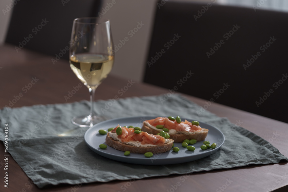 Bruschettas with cream cheese and salmon with glass of white wine on dining table