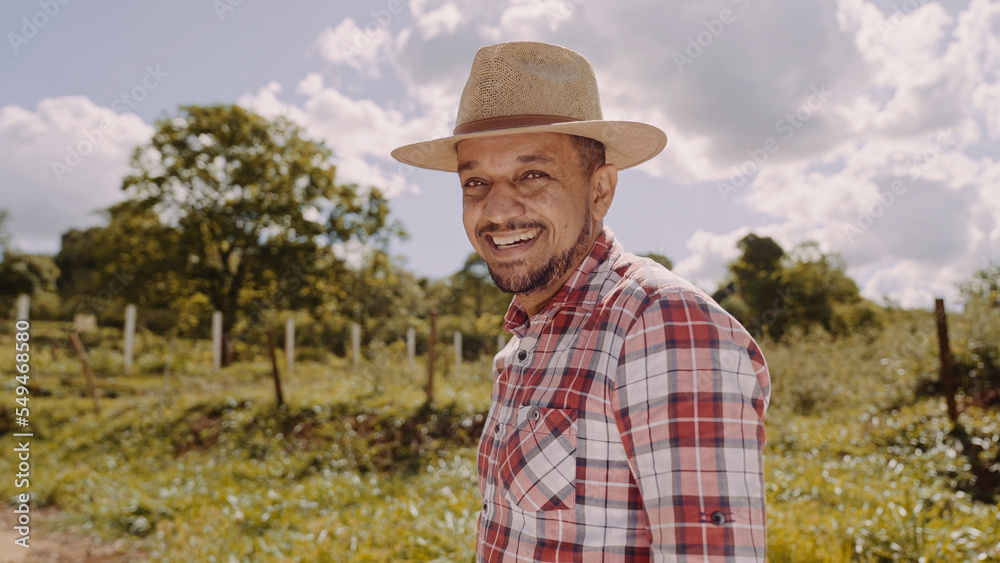 Portrait of young farmer man in the casual shirt and hat in the farm