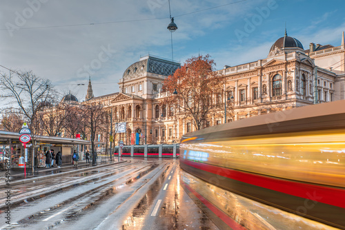 Tram moving on a street in the foreground - View of the University of Vienna (Universitat Wien) - Vienna, Austria  photo
