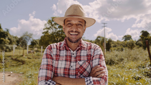 Portrait of young farmer man with crossing hands in the casual shirt and hat in the farm