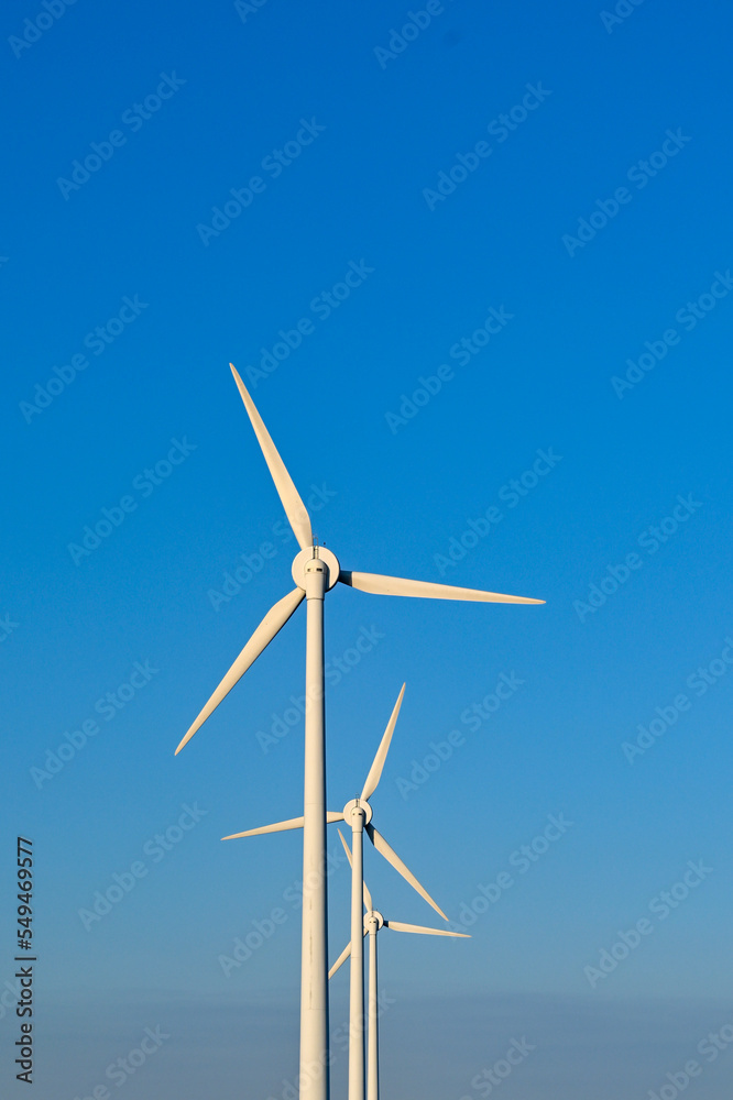 Tall wind turbines isolated against a deep blue sky. No people.