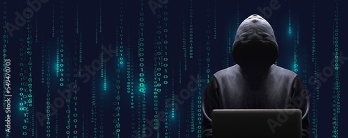Silhouette décalée sur la droite du cybercriminel devant son écran d'ordinateur portable sur fond de données binaires noire