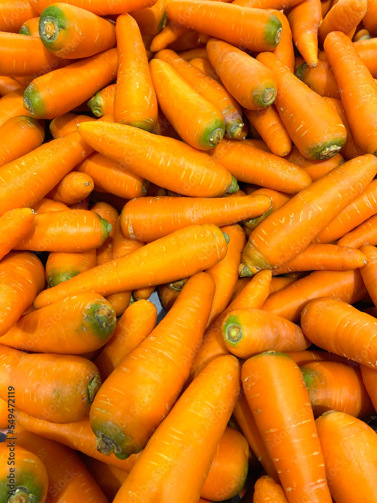 Lots of raw carrots close up at the market. Fresh organic vegetables in the supermarket. Harvest concept Lots of raw carrots close up at the market. Fresh organic vegetables in the supermarket. Harvest concept