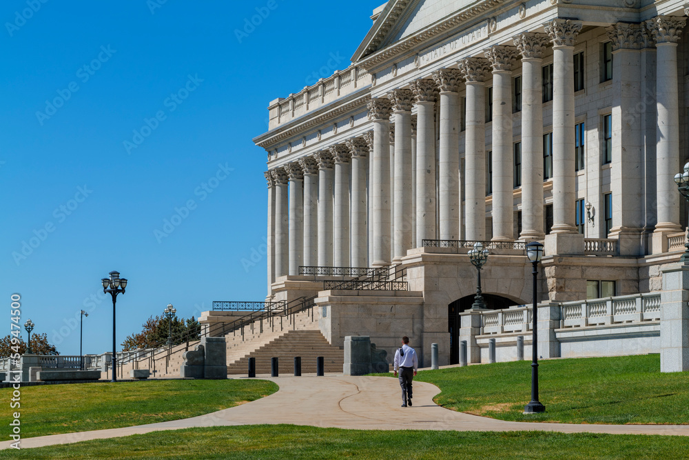 A lone man walks away in front of the Capitol building on a sunny day. High-quality photo
