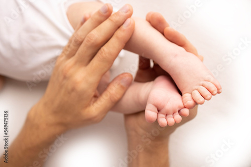 Children's foot in the hands of mother, father, parents. Feet of a tiny newborn close up. Little baby legs. Mom and her child. Happy family concept. Beautiful concept image of motherhood stock photo.  © Vad-Len
