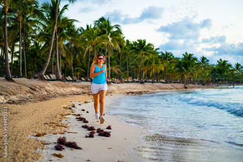 Woman running on sunny  tropical beach at daybreak 