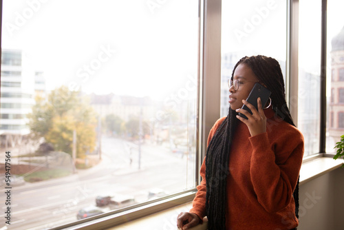 Young, African woman in the office is using phone