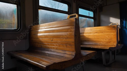 Slow Motion Wooden seats in an empty coach of suburban train without people, that rides in the forest photo