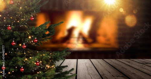 Weihnachtsbaum im Vordergrund vor einem unscharfen Wohnzimmer mit Kaminfeuer
