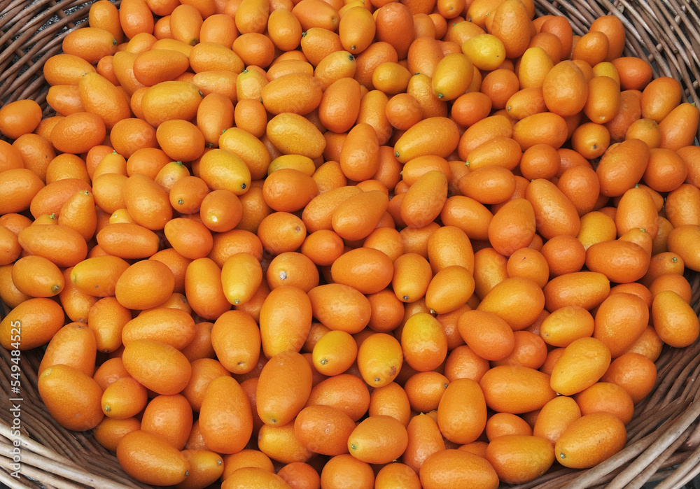 A straw basket with fresh kumquat on street pavers. A straw basket with fresh kumquat on street pavers.