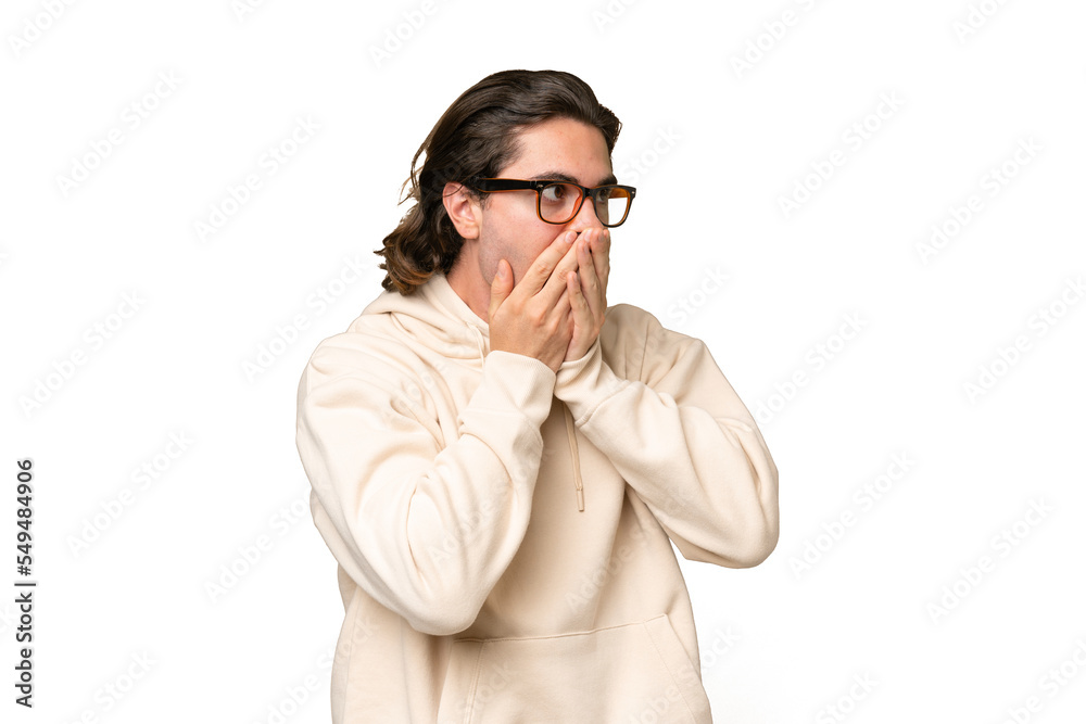 Young caucasian man isolated on green chroma background covering mouth and looking to the side