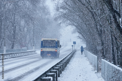 Vehicles on street during snowfall. Heavy snowfall, cars driving on slippery snow-covered road on city street. Slippery highway on a cold snowy winter day. Snowstorm on the road, poor visibility.   photo