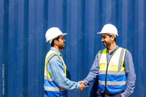 Two professional male engineers in helmets and uniforms shaking hands after signing a contract. Handshake as a symbol of greeting, congratulation, approval and farewell.