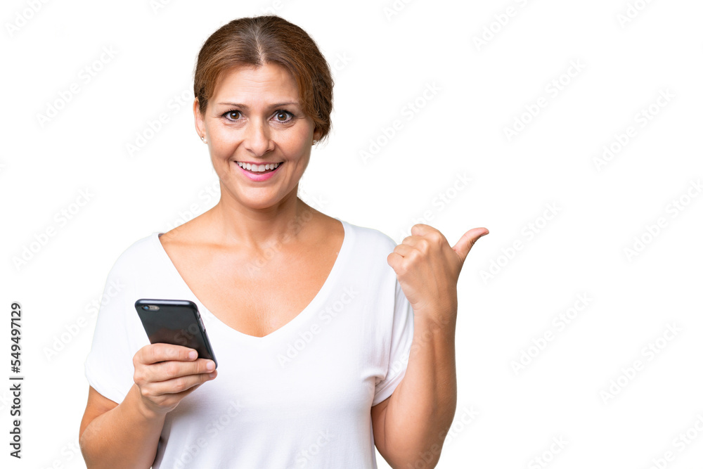 Middle-aged caucasian woman over isolated background using mobile phone and pointing to the lateral Middle-aged caucasian woman over isolated background using mobile phone and pointing to the lateral