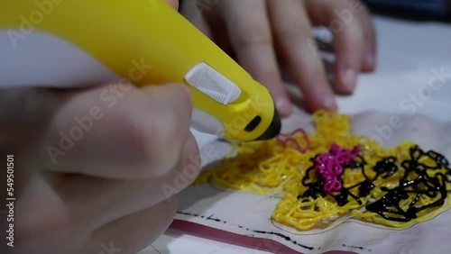 Close-up of 3D pens in the hands of a child. The child draws with a 3D pen.