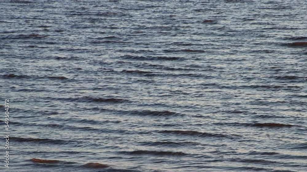 Calm waves of the ocean reflecting the sunlight during sunset for moody background Calm waves of the ocean reflecting the sunlight during sunset for moody background