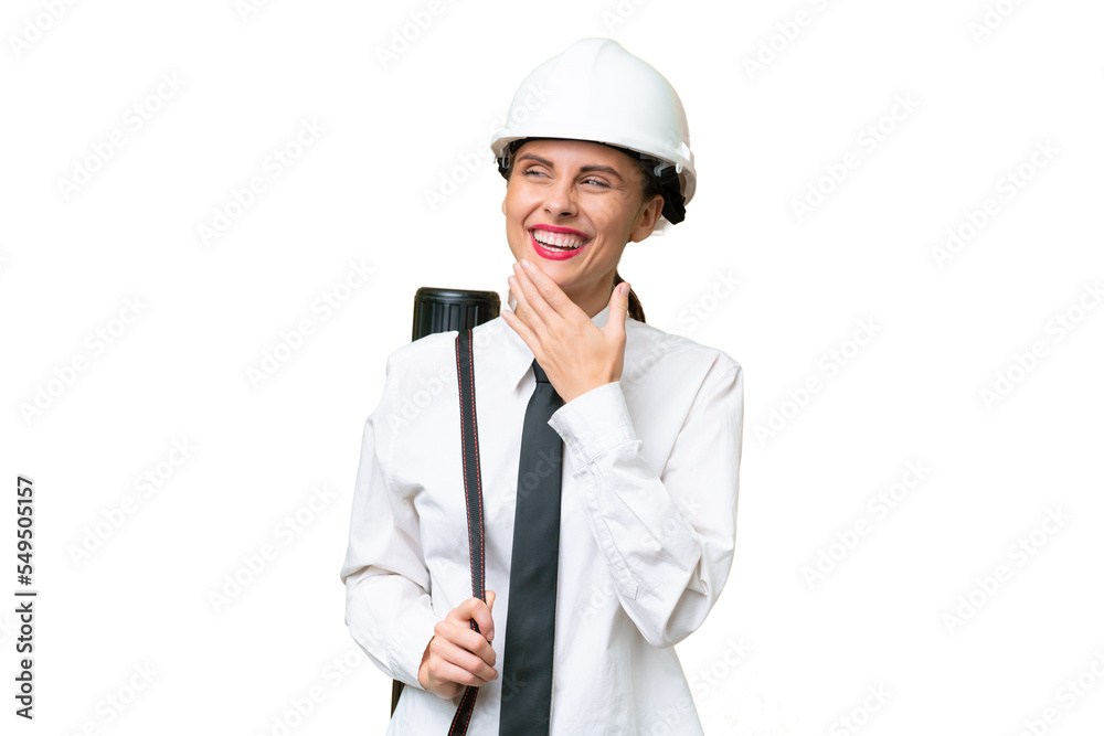 Young architect woman with helmet and holding blueprints over isolated background looking up while smiling Young architect woman with helmet and holding blueprints over isolated background looking up while smiling
