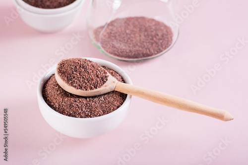 Black Himalayan kala namak salt in bowl with wooden spoon on pink background