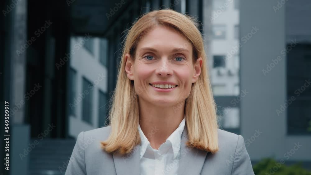 Close-up caucasian woman standing outdoors successful businesswoman professional lawyer corporate employee happy client smiling looks at camera posing in front office building female business portrait Close-up caucasian woman standing outdoors successful businesswoman professional lawyer corporate employee happy client smiling looks at camera posing in front office building female business portrait