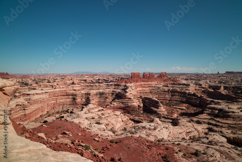 View from the Maze Overlook in the Maze District of Canyonlands National Park in, Utah. A few clouds are seen on the horizon in an otherwise clear sky. A labyrinth of canyons is visible.