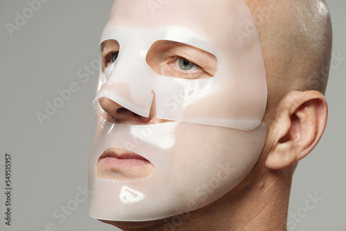 Mature man using moisturising hydrogel collagen mask on face looking away  photo