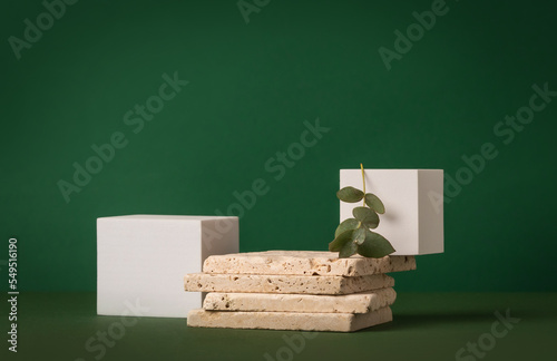 Product presentation mockup scene made with travertine tiles, white cubes and eucalyptus branch on a green background. Front view, copy space. photo