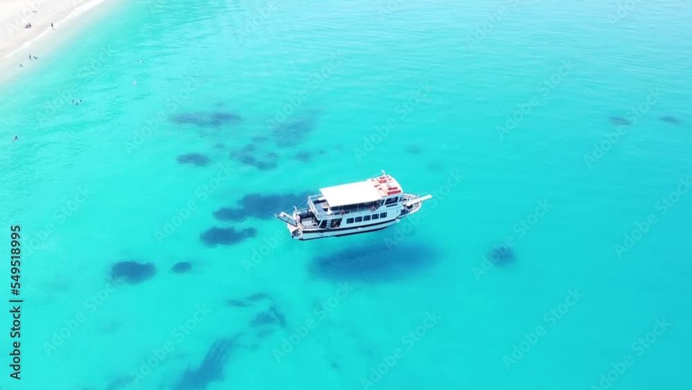 Aerial View of a little boat floating on transparent turquoise waters in the azure sea on a Greek island Aerial View of a little boat floating on transparent turquoise waters in the azure sea on a Greek island