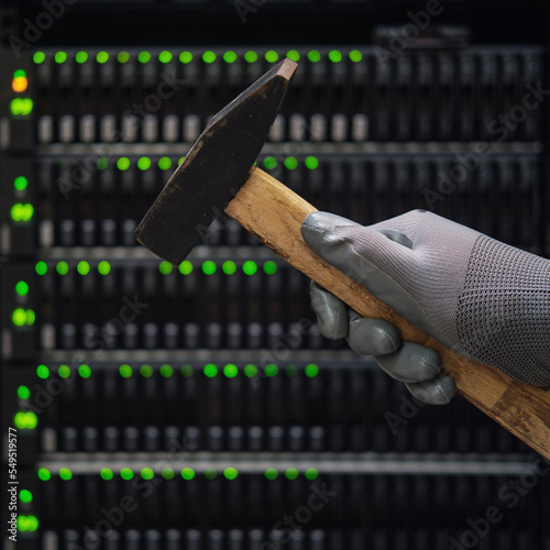 Hammer in the hands of a man at the server for storing data, close-up photo