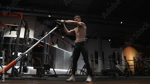 muscular sportsman in sport gym do landmine exercise. sport sportsman with barbell landmine in gym photo