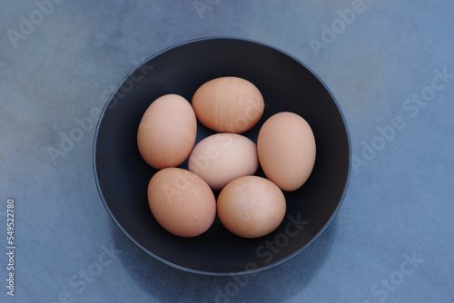 Six brown eggs in a black bowl