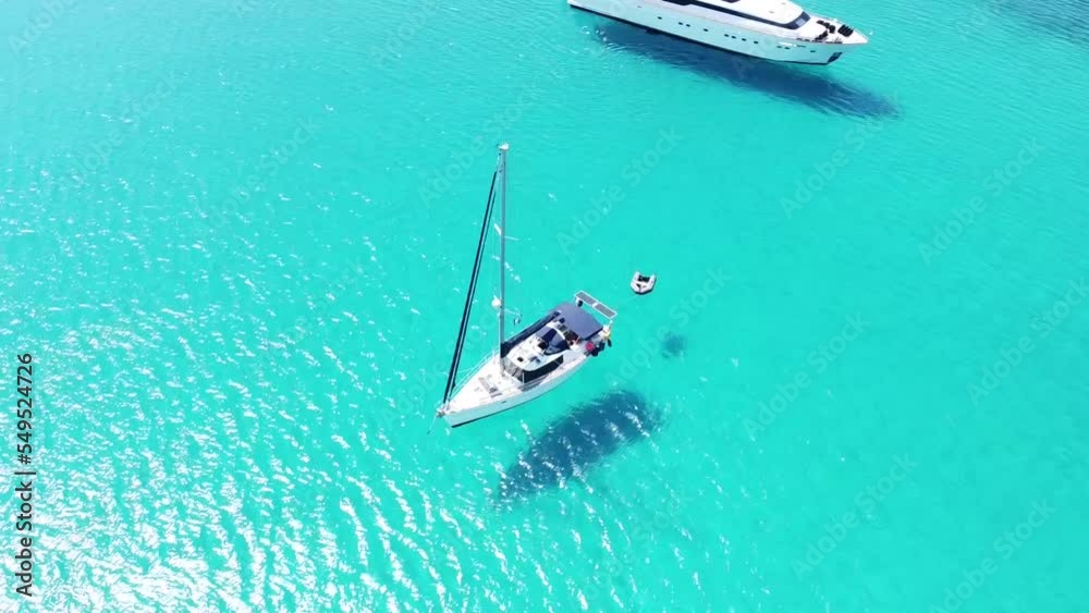 Rounded dron shot: Aerial view of a little boat floating on transparent turquoise waters in the crystal-clear sea of Greece Rounded dron shot: Aerial view of a little boat floating on transparent turquoise waters in the crystal-clear sea of Greece