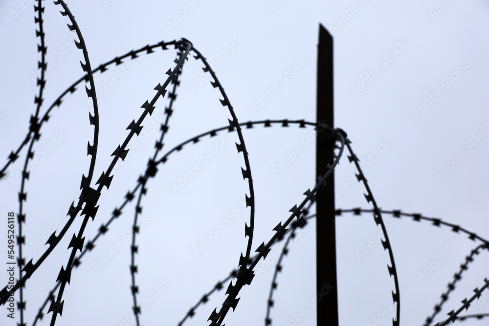 Barbed wire on sky background. Concept of boundary, prison, war or military base Barbed wire on sky background. Concept of boundary, prison, war or military base