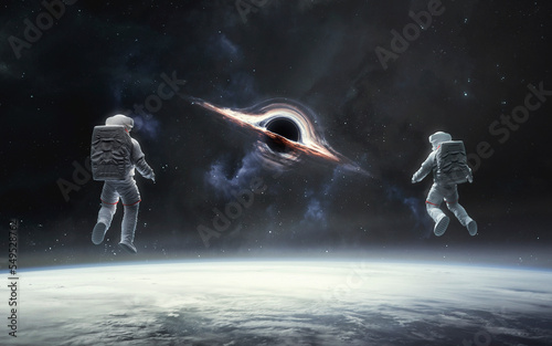 3D illustration of astronaut looks in giant black hole at Earth orbit. 5K realistic science fiction art. Elements of image provided by Nasa