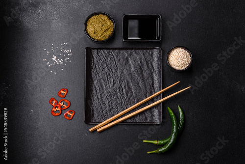 Empty plate with wooden sticks for Asian food on a dark concrete background