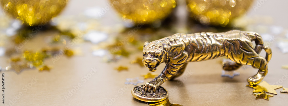 Banner with bronze figure of a tiger with a coin on a background of stars, golden shiny balls, copy space Banner with bronze figure of a tiger with a coin on a background of stars, golden shiny balls, copy space