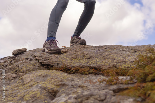 Woman feet which hiking in over rocky mountains. Low angle view