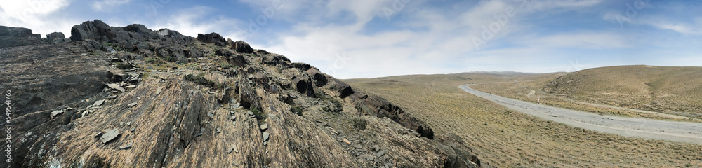 Panorama of wide top view from the rock of steppe landscape: road between hills going beyond horizon