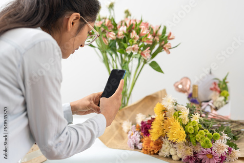 Crop florist taking photo of flowers photo