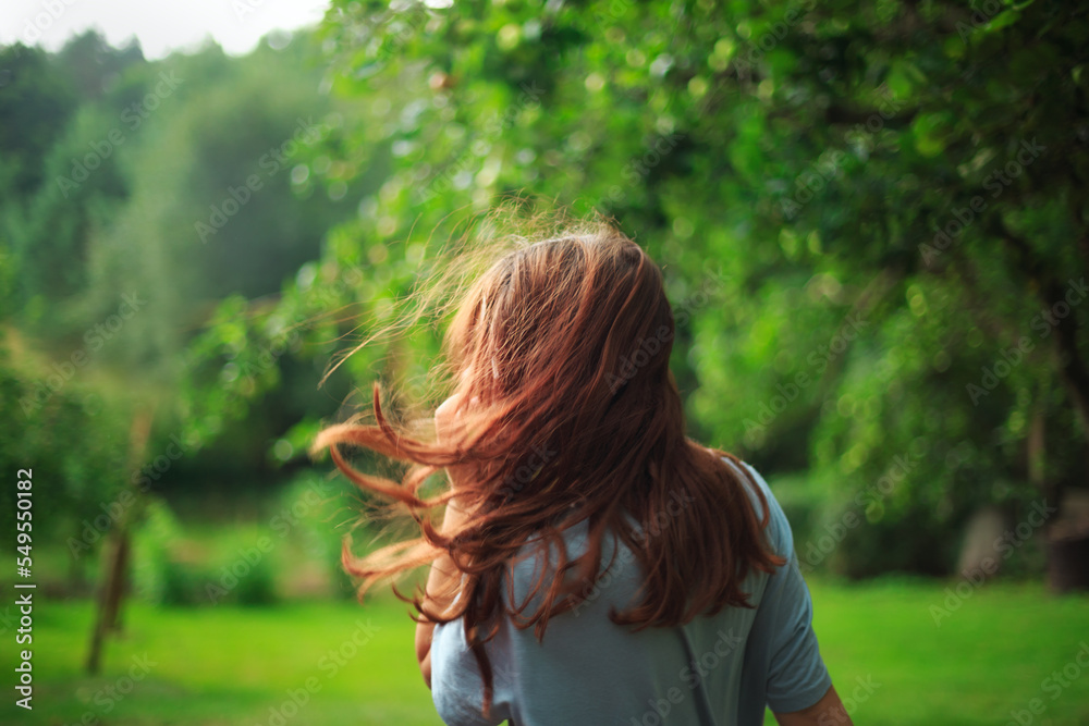 Girl with red hair blowing in the wind breathing deeply and looking away with a blurred nature background. Soft focused Girl with red hair blowing in the wind breathing deeply and looking away with a blurred nature background. Soft focused