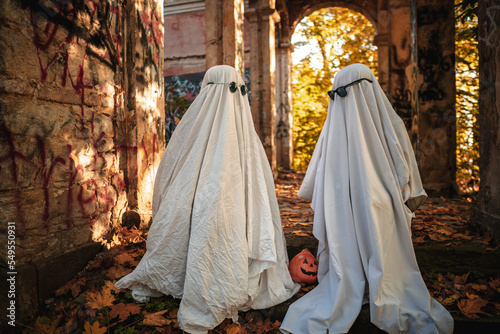 A funny image of two people in ghost costumes and sunglasses in an abandoned building