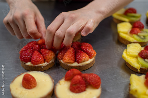 Close-up view of pastry chef hands decorating a cake
