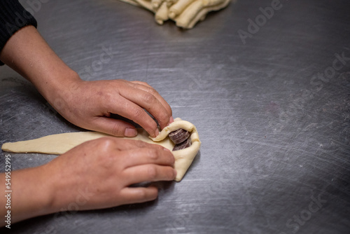 Pastry chef hands making chocolate croissants.