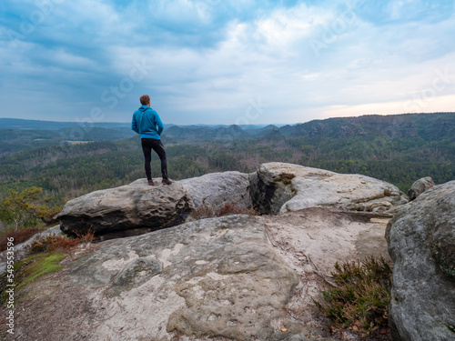 Man runner in black leggings and blue sweatshirt stay at sharp rocky edge