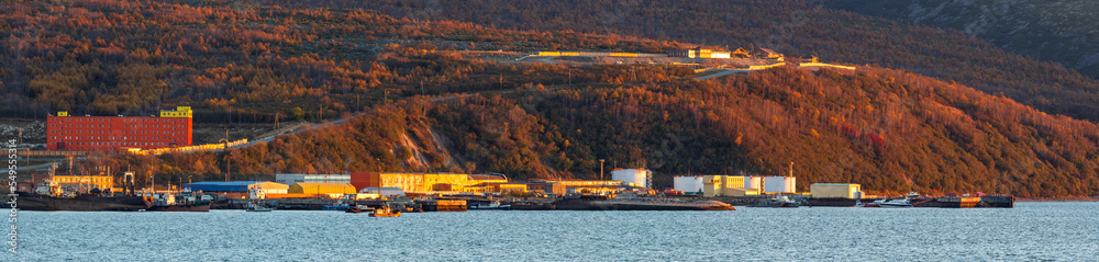 Autumn panoramic landscape of the coast. Ships and boats near the pier. There are large fuel tanks on the shore. Fishing port in Nagaev bay, Sea of Okhotsk, Magadan city, Magadan region, Russia. Autumn panoramic landscape of the coast. Ships and boats near the pier. There are large fuel tanks on the shore. Fishing port in Nagaev bay, Sea of Okhotsk, Magadan city, Magadan region, Russia.