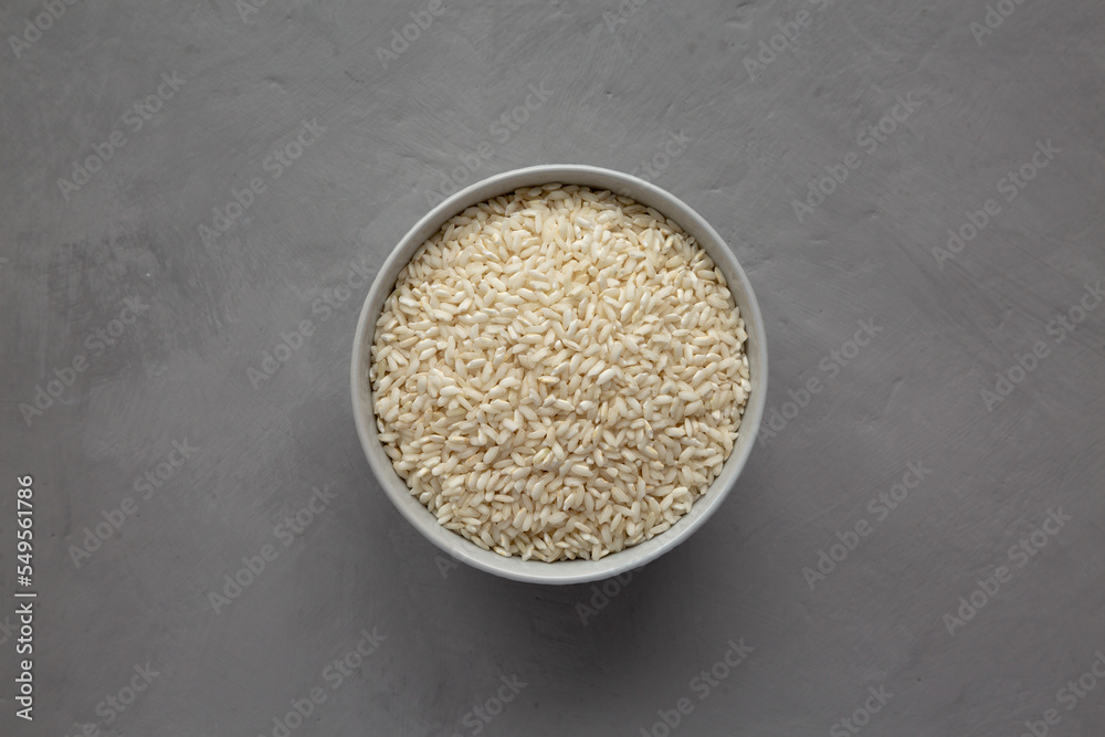Raw Organic Carnaroli Rice in a Bowl on a gray background, top view. Overhead, from above, flat lay. Raw Organic Carnaroli Rice in a Bowl on a gray background, top view. Overhead, from above, flat lay.