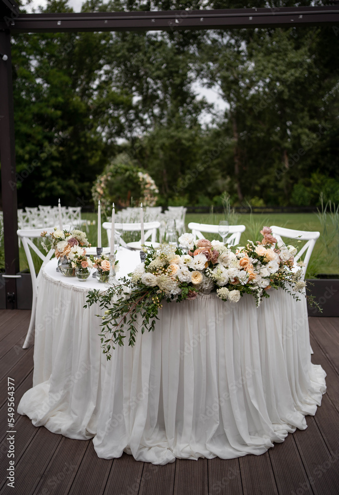 Main table at a wedding reception with beautiful fresh flowers. Outside wedding decorations.
